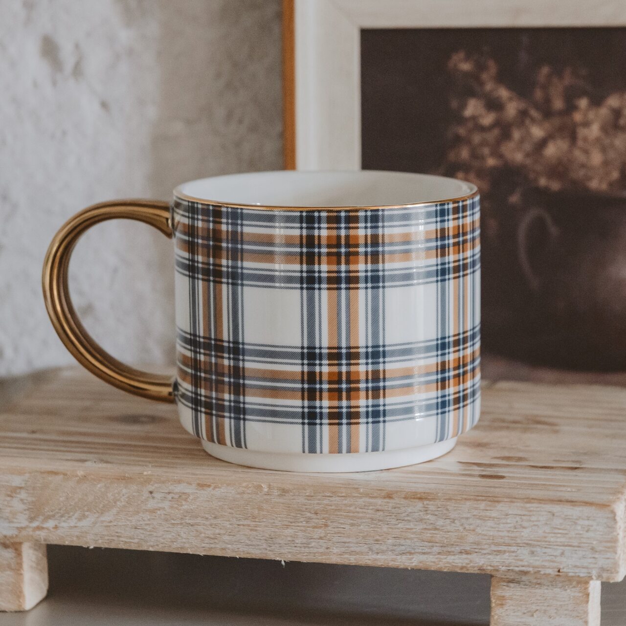 Eine warme, saisonale Tasse | klassisch orange und marineblau kariert | auf cremefarbenem Hintergrund | veredelt mit einem eleganten goldenen Griff.