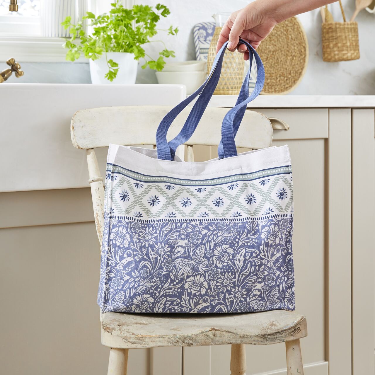 Die Ulster Weavers Canvas-Schultertasche Küstenschätze zeigt ein florales Muster mit Küstenvögeln und Käfern in einer zartem beige-grün-blauen Farbpalette